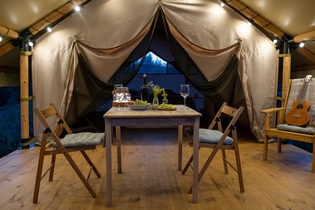 Served table and two chairs prepared for romantic dinner inside large glamping tent