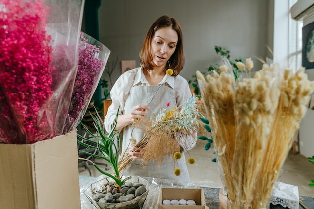 Young woman florist wearing apron making bouquet