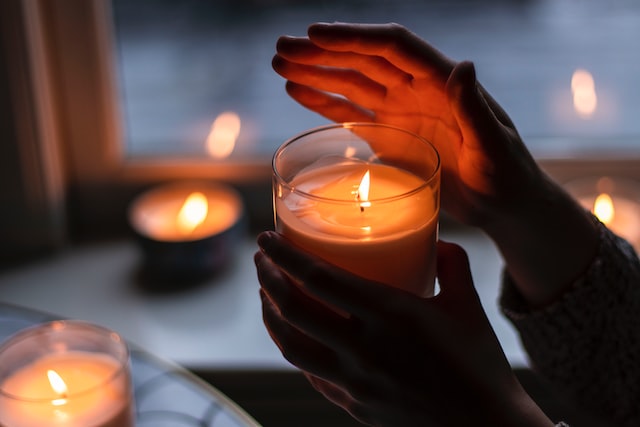 a person holds a candle in a jar
